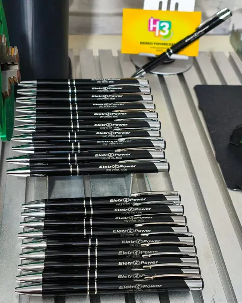 Canetas pretas metalizadas com a logo da Eletro Power gravada a laser, enfileiradas na bancada